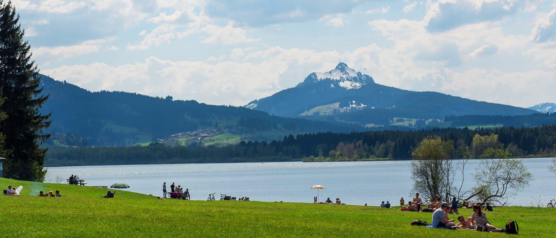 Badesee im Allgäu mit Bergen im Hintergrund