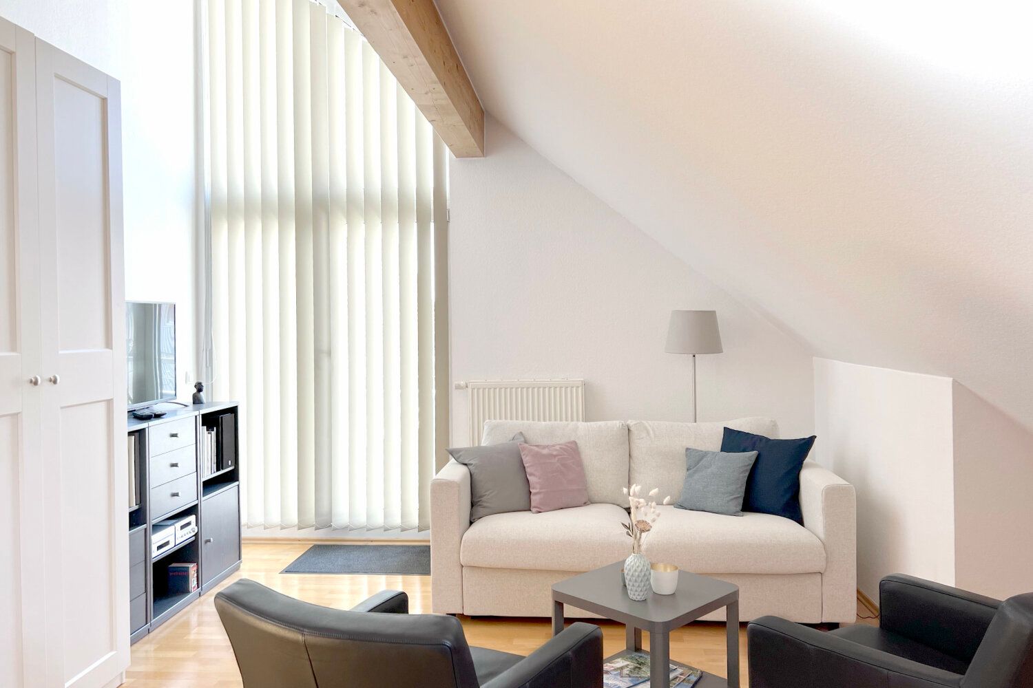 Wohn- und Schlafbereich mit Sofa und Sesseln unter der Dachschräge